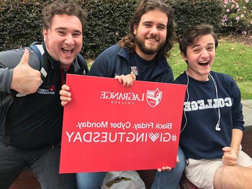 Three students pose with a #GivingTuesday sign