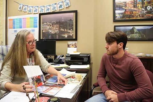 Michele Raphoon, right, speaks with a student in her office