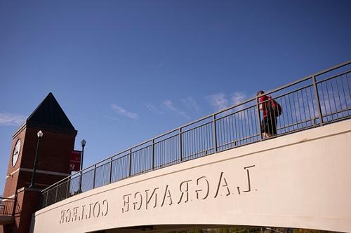 student crossing the LaGrange College pedestrian bridge, which has the college name etched on the side